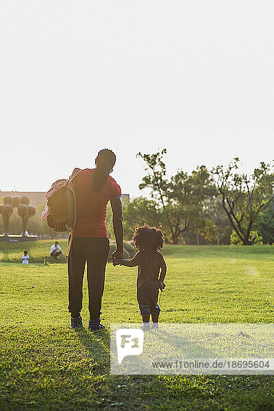 Father and son standing on grass in park at sunny day