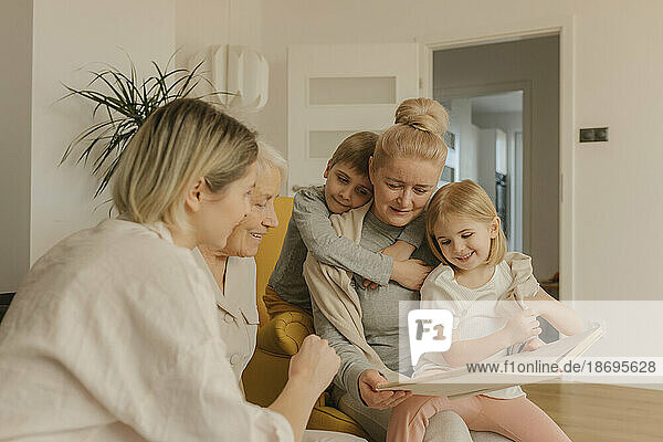 Multi-generation family enjoying watching photo album sitting at home