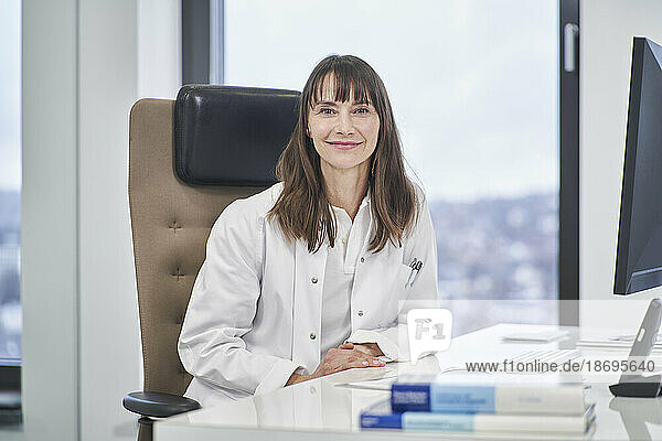 Portrait of confident female doctor sitting at desk in medical practice