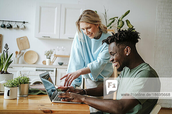 Smiling man sharing laptop with girlfriend at home