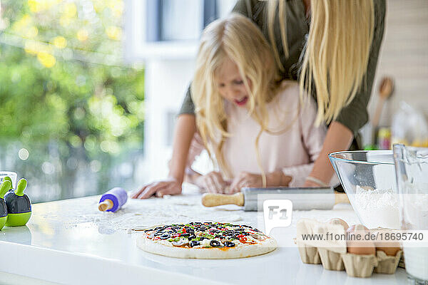 Fresh pizza with mother and daughter in kitchen at home