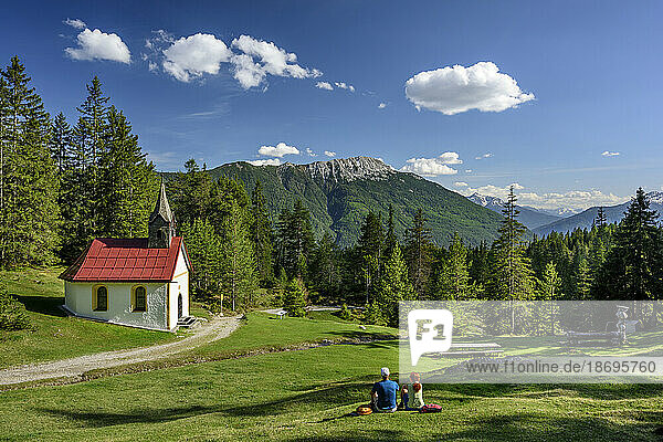 Austria  Tyrol  Hiking pair resting in front of alpine chapel