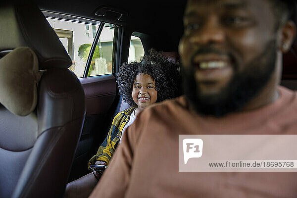 Smiling father and daughter sitting in car