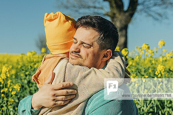 Vater und Sohn umarmen sich am Rapsfeld