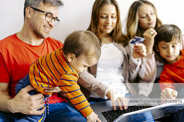 Family spending leisure time together with laptop at home