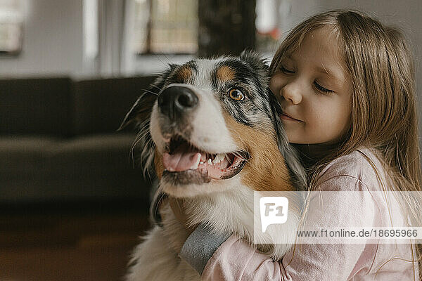 Mädchen umarmt australischen Schäferhund zu Hause