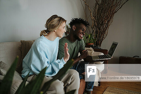 Happy couple gesturing on video call through laptop at home
