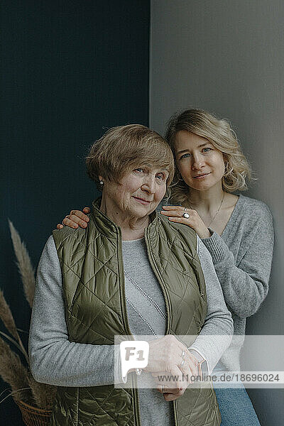 Enkelin lehnt mit Großmutter zu Hause an der Wand