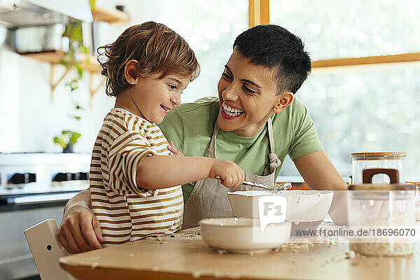 Son mixing flour by happy mother at home