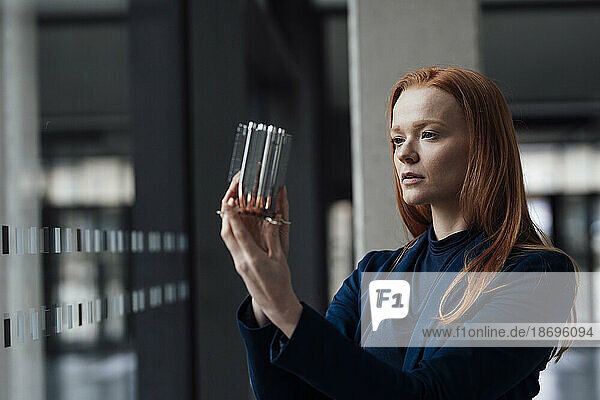 Redhead businesswoman examining machine part at office