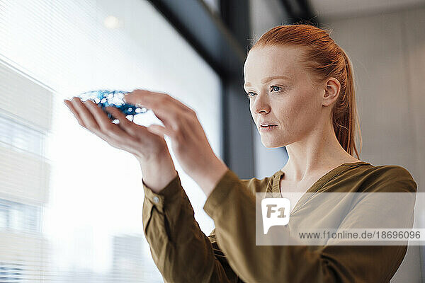 Young businesswoman examining machine part at office