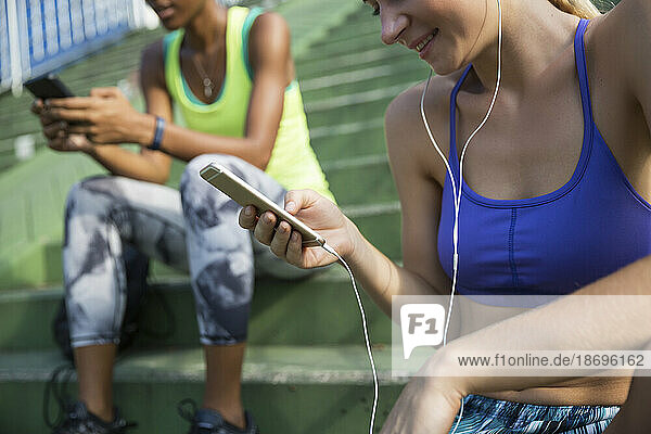 Smiling woman listening music with wired headphones through smart phone