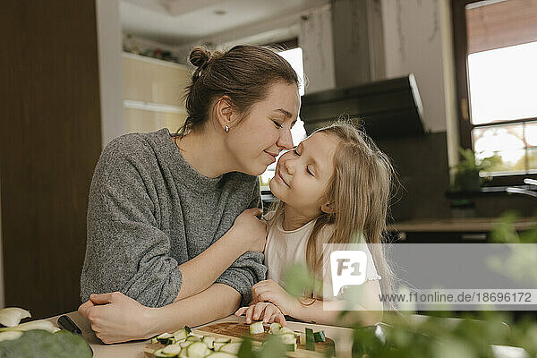 Mother kissing daughter in kitchen