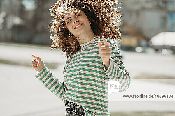 Smiling woman dancing and gesturing at sunny day