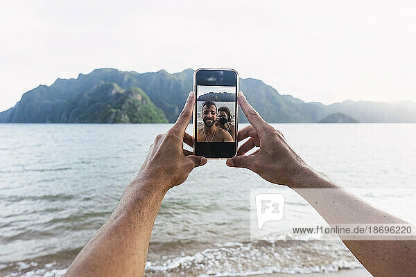 Couple taking selfie through smart phone at vacation