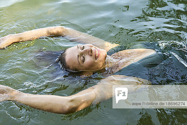 Lächelnde Frau schwimmt auf dem Wasser im See
