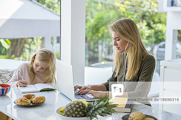Freelancer working with daughter doing homework at home