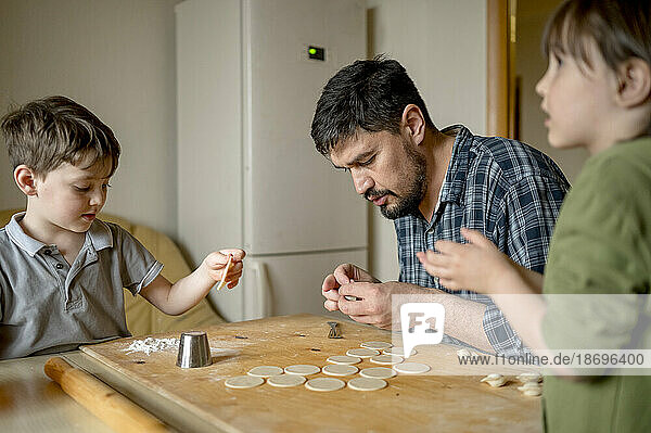 Father teaching sons to make dumplings at home