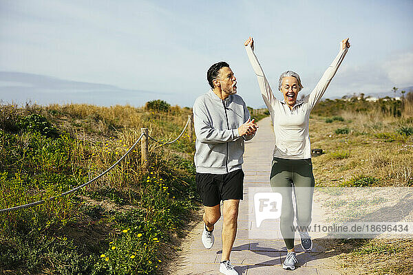 Mature man applauding by woman jogging at beach