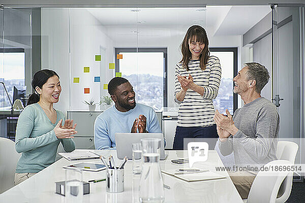 Colleagues applauding on video conference in office meeting
