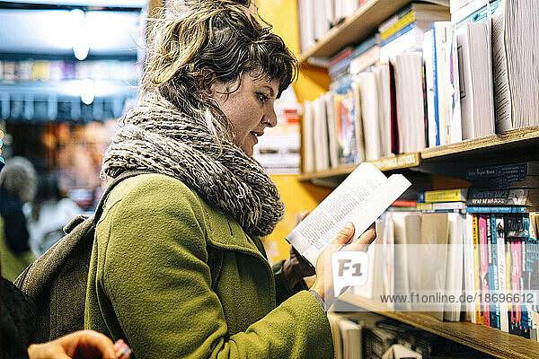 Woman wearing scarf reading book in library
