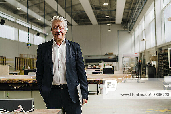 Smiling senior businessman standing in carpentry factory