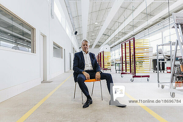Businessman sitting on chair in factory