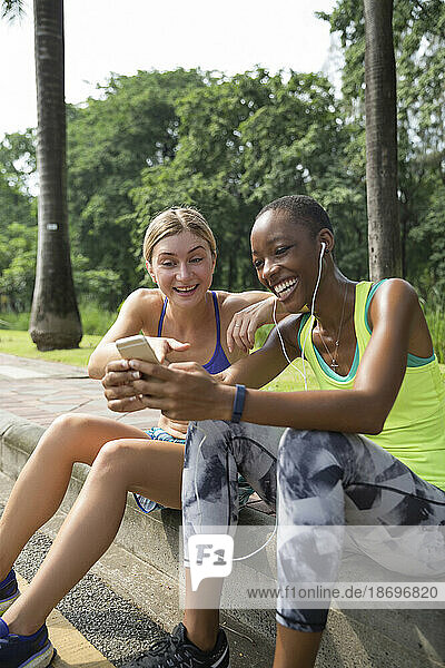Fröhliche Freunde teilen ihr Smartphone im Park