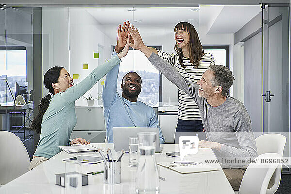 Happy colleagues giving high-five in office meeting