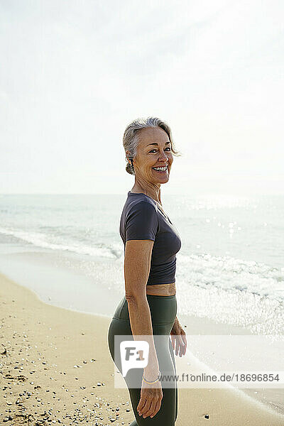 Smiling mature woman standing at beach