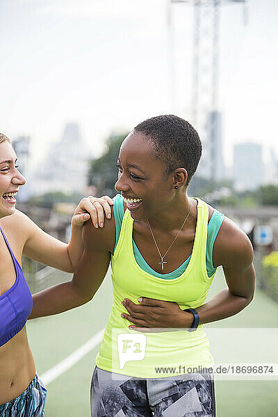 Happy woman in sports clothing laughing with friend