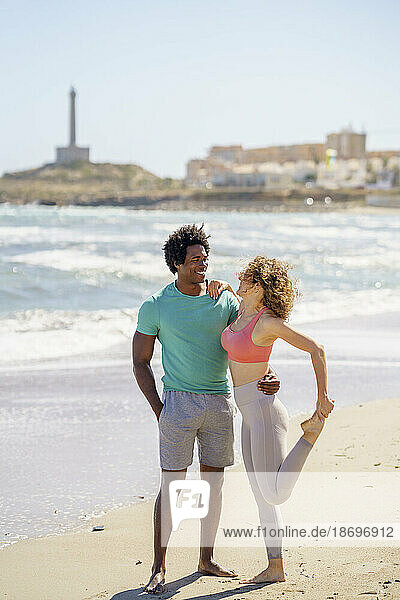 Smiling couple standing face to face with arms around at seashore