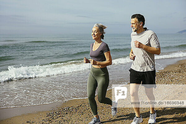 Mature couple jogging together at sunny day