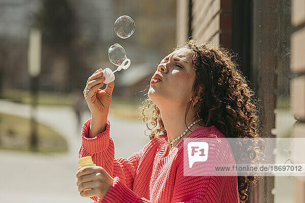 Young woman blowing soap bubbles through wand