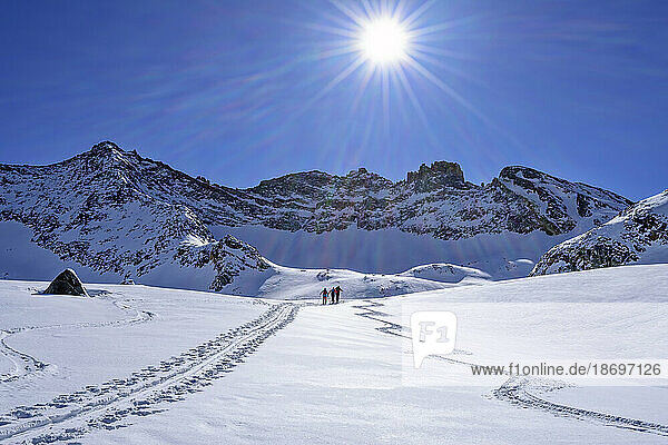 Austria  Tyrol  Sun shining over skiers traveling through snow at Hollensteinkar