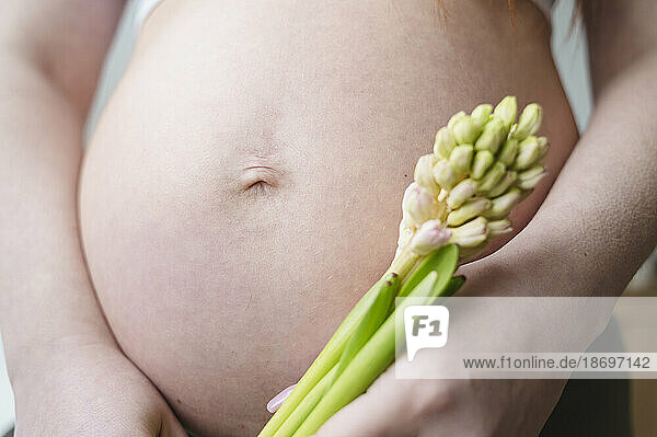 Pregnant woman holding flowers in hand