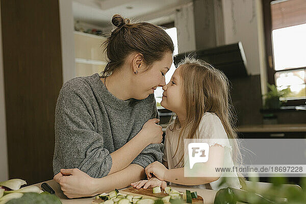 Mother and daughter rubbing noses in kitchen