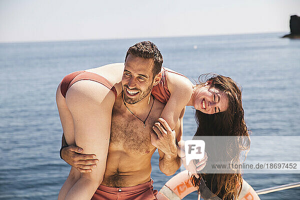 Lächelnder Mann  der im Urlaub Spaß mit seiner Freundin auf dem Boot hat