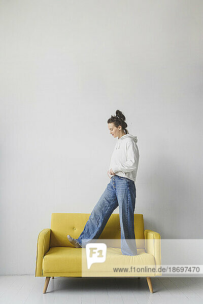 Woman dressed in casual clothing walking on yellow sofa