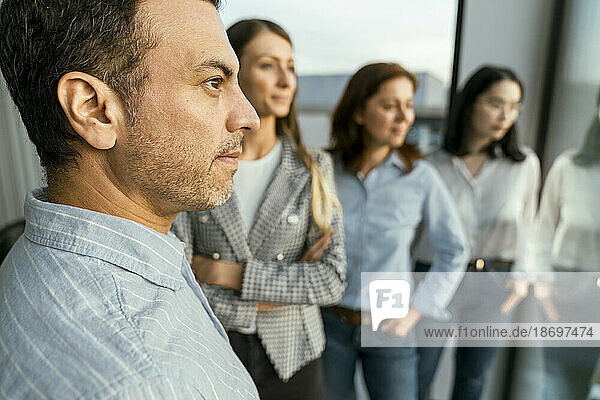 Thoughtful business team looking out of window in office