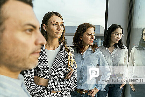 Thoughtful business team looking out of window in office