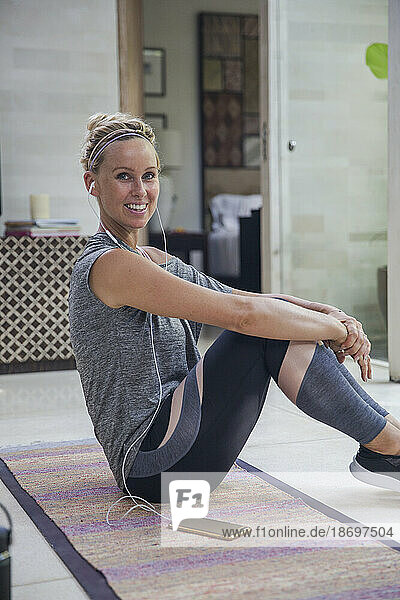 Smiling woman sitting on exercise mat at home