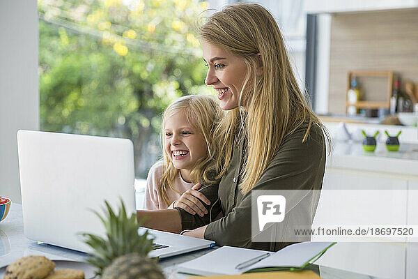 Glückliche Frau  die zu Hause den Laptop ihrer Tochter benutzt