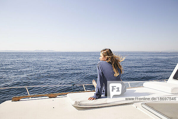 Frau sitzt an sonnigem Tag auf Bootsdeck