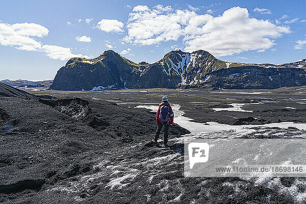 Woman standing on a glacier looking out at the mountainous landscape on the South Coast of Iceland; Vik  South Iceland  Iceland