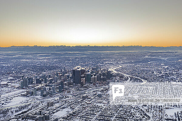 City of Calgary in a blanket of snow at sunset  with silhouetted Rocky Mountains in the distance  in Alberta  Canada; Calgary  Alberta  Canada