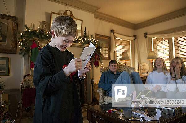 Young boy receives a birthday card and present in his home while his family watches; Lincoln  Nebraska  United States of America