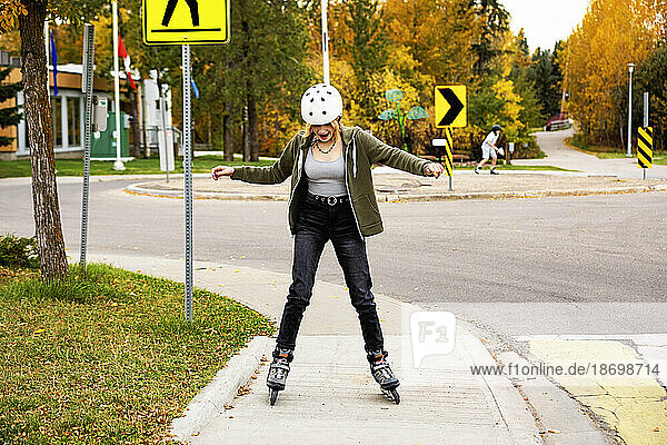 Teenage girl inline skating in a city park during a warm fall day; St. Albert  Alberta  Canada