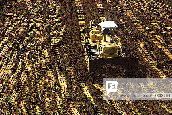 Elevated view of bulldozer and it's tracks on cleared land; United States of America