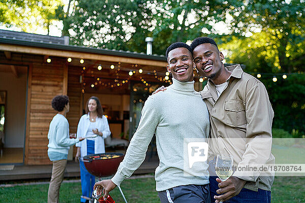 Portrait happy young gay male couple enjoying barbecue in backyard
